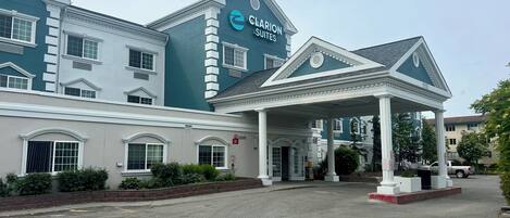 A hotel with a covered entrance, multiple windows, and a sign for 'Clarion Suites'.