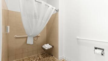 Une salle de bain équipée d’un rideau de douche, d’un porte-serviettes, d’une barre d’appui et d’un porte-rouleau de papier toilette.