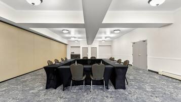Una sala de conferencias con una larga mesa, sillas e iluminación en el techo.