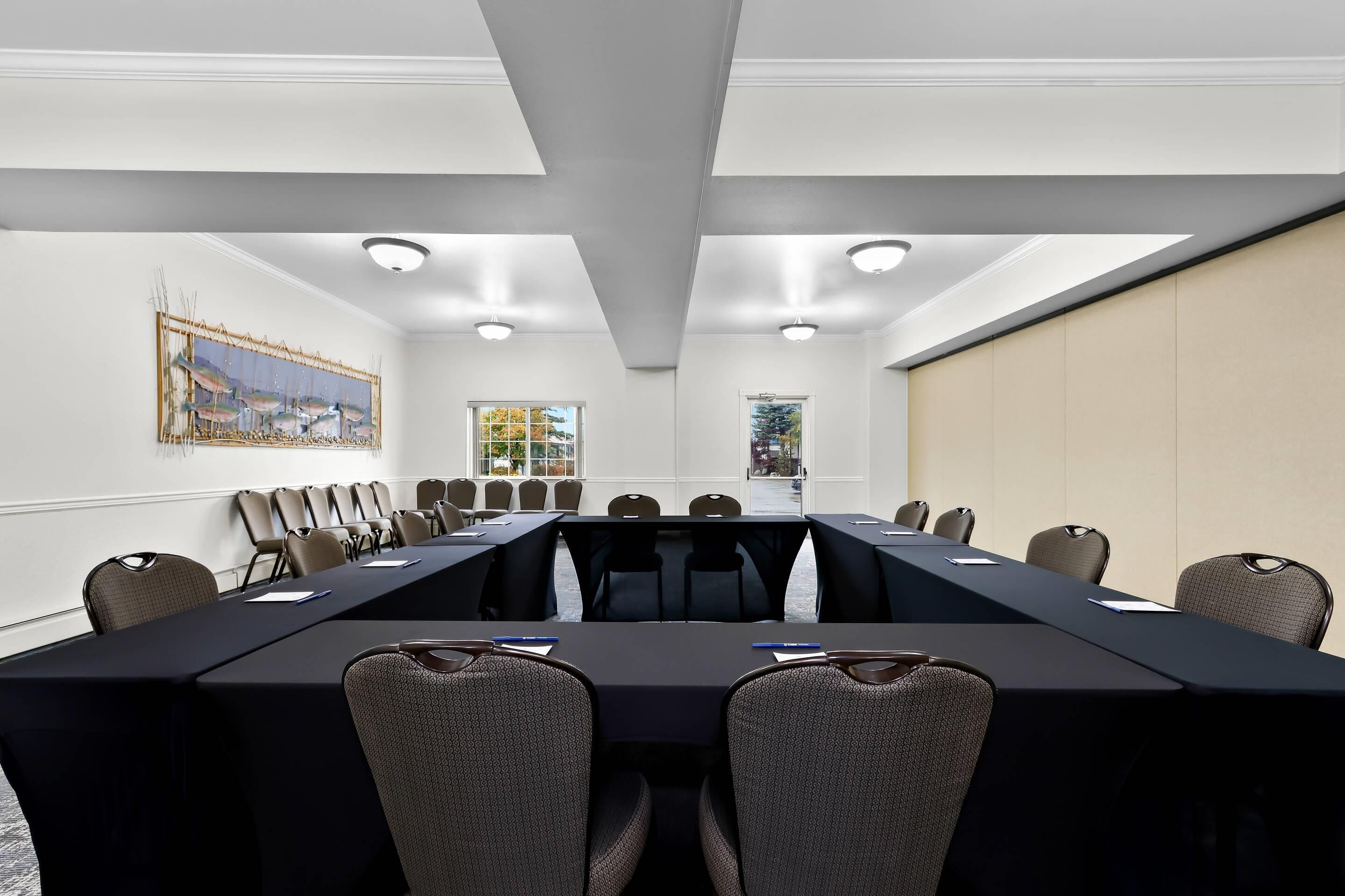 Un salón de conferencias con una larga mesa, sillas y un cuadro en la pared.