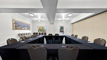 Ein Konferenzraum mit einem langen Tisch, Stühlen und einem Bild an der Wand.