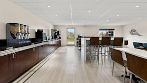 A modern kitchen with a long counter, coffee machines, and a view of the outdoors through a door. - Clarion Suites Anchorage Downtown (Anchorage)