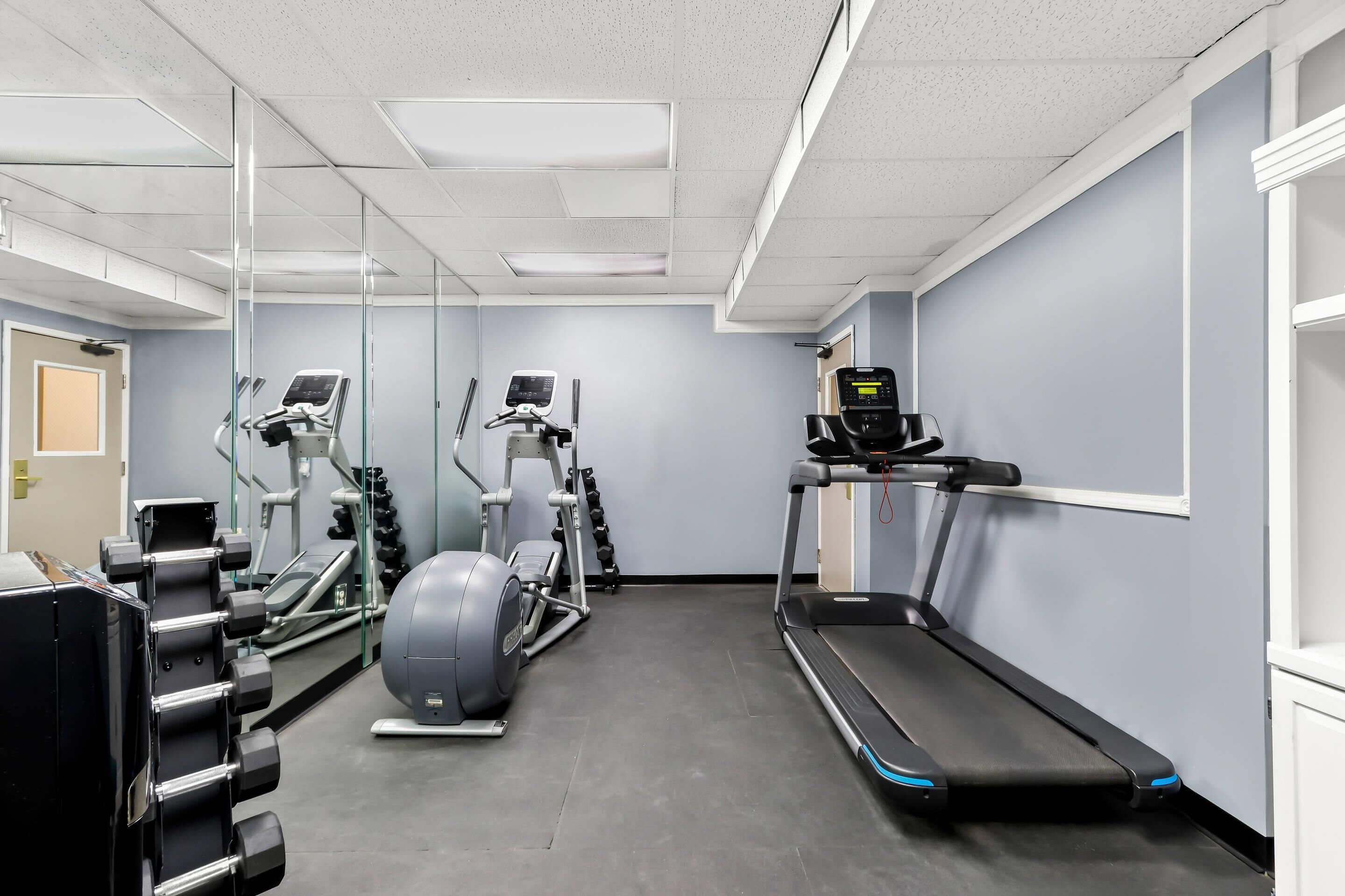 A gym with exercise equipment including treadmills, elliptical machines, and weight machines.