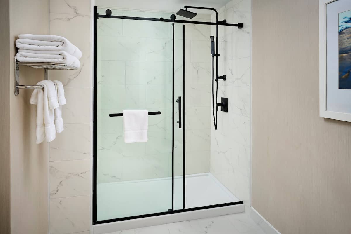 A modern bathroom with a glass-enclosed shower, marble tiles, and neatly arranged towels.