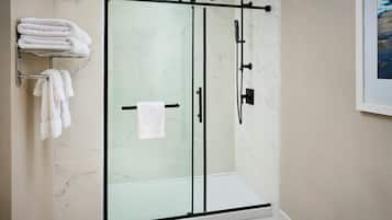 A modern bathroom with a glass-enclosed shower, marble tiles, and neatly arranged towels.