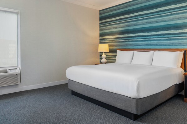 A hotel room with a bed, a lamp, a window, and a wall with a striped pattern. - Niagara Fallsview Hotel (Niagara Falls)