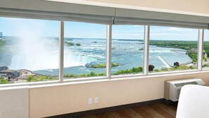 A room with a large window overlooking a waterfall and river, a radiator, and a carpeted floor. - Niagara Fallsview Hotel (Niagara Falls)