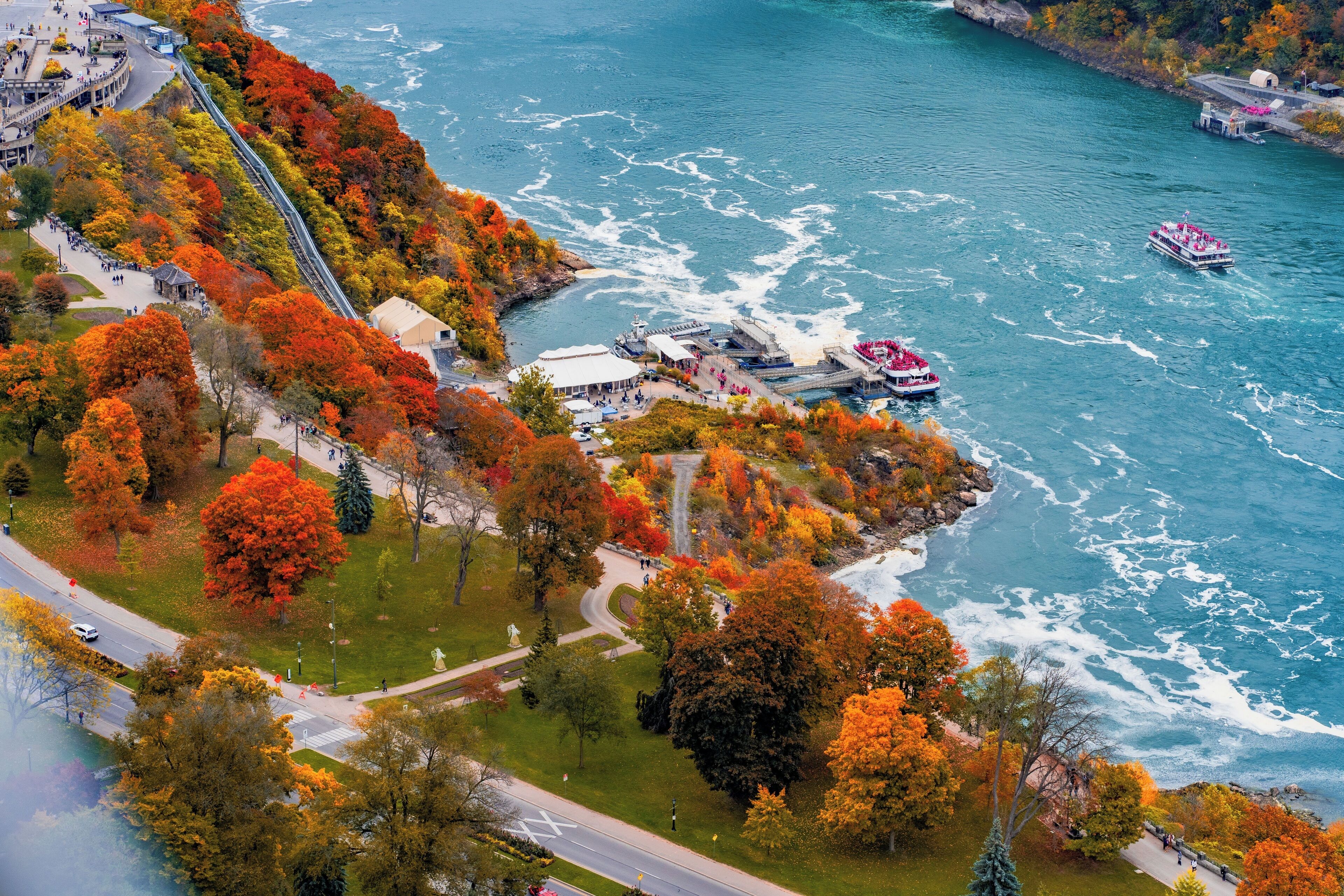 An aerial view of a waterfront area with a river, a pedestrian bridge, and a boat dock.