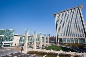 Un hôtel moderne doté d’une façade en verre remarquable, d’une cour intérieure et d’un immeuble imposant à la structure rectangulaire, avec de nombreuses fenêtres.