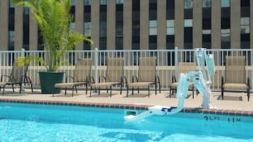 A swimming pool with a lifeguard stand, lounge chairs, and a palm tree.