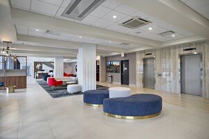A modern lobby with a central seating area, a reception desk, and elevators.