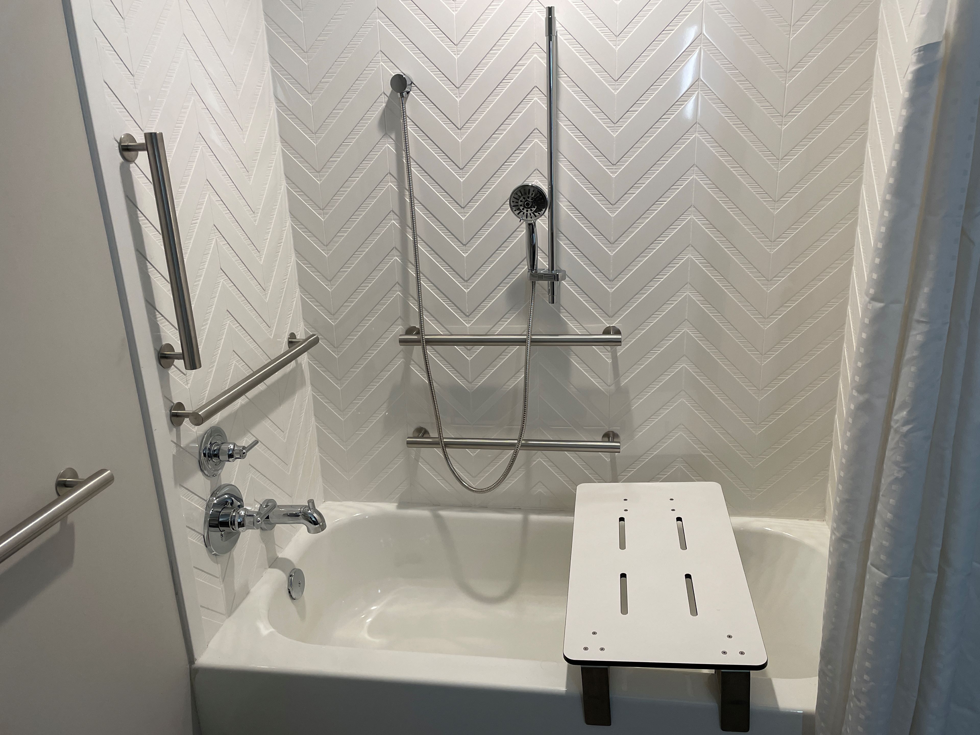 A modern shower area with a built-in bathtub, chrome fixtures, and a chevron-patterned wall.