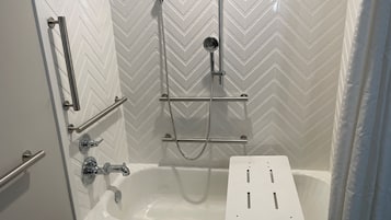 A modern shower area with a built-in bathtub, chrome fixtures, and a chevron-patterned wall.