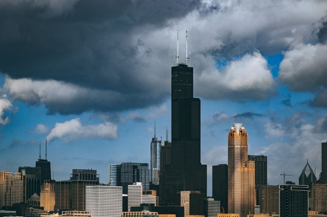 A city skyline with multiple high-rise buildings, including a prominent skyscraper with antennas.