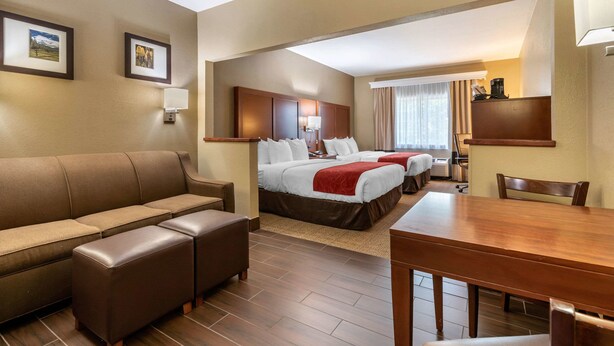 A hotel room with a sofa, two beds, a dining table, and a small kitchen area. - Comfort Suites Fort Collins Near University (Fort Collins)