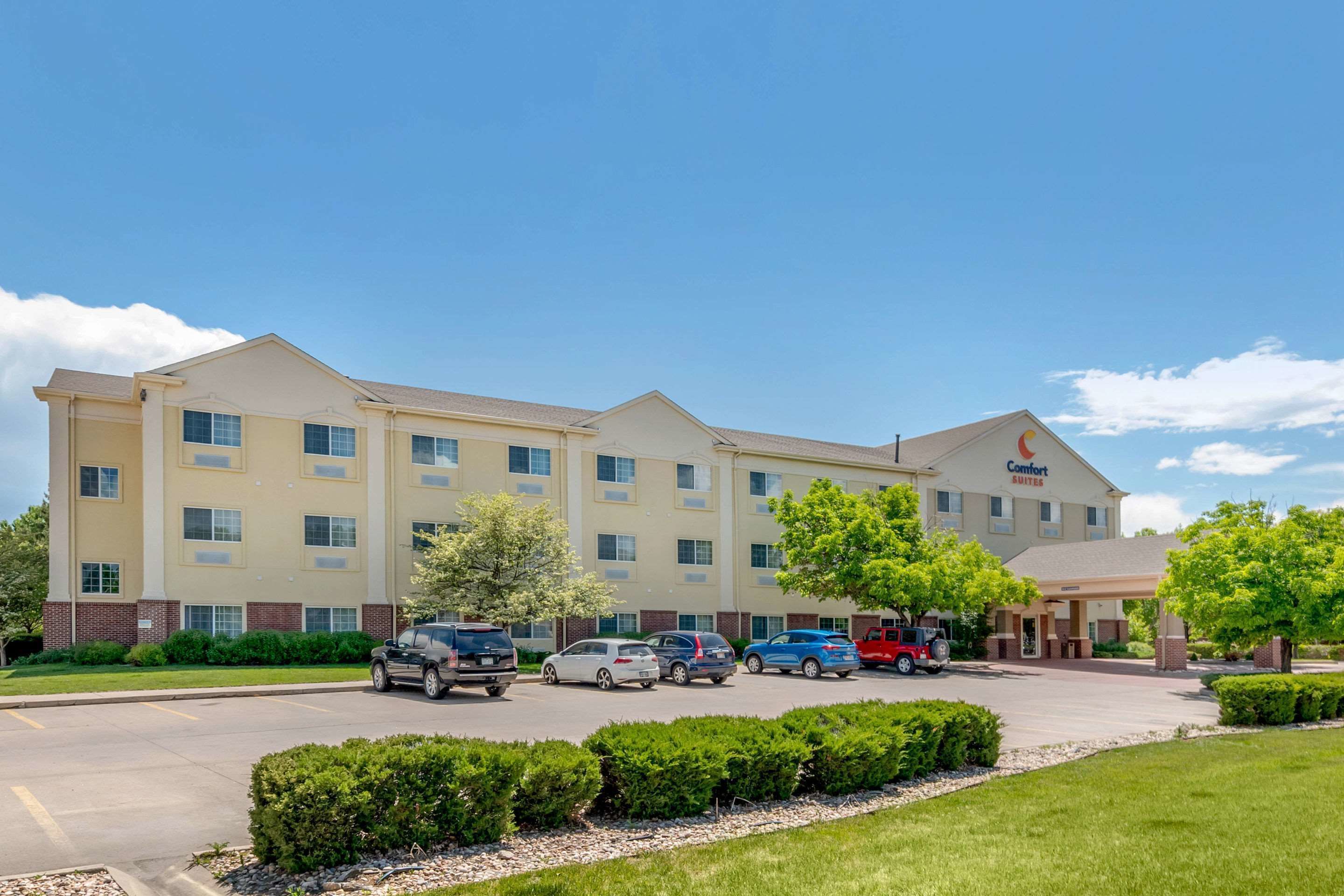 A multi-story hotel with a parking lot and several cars parked in front.
