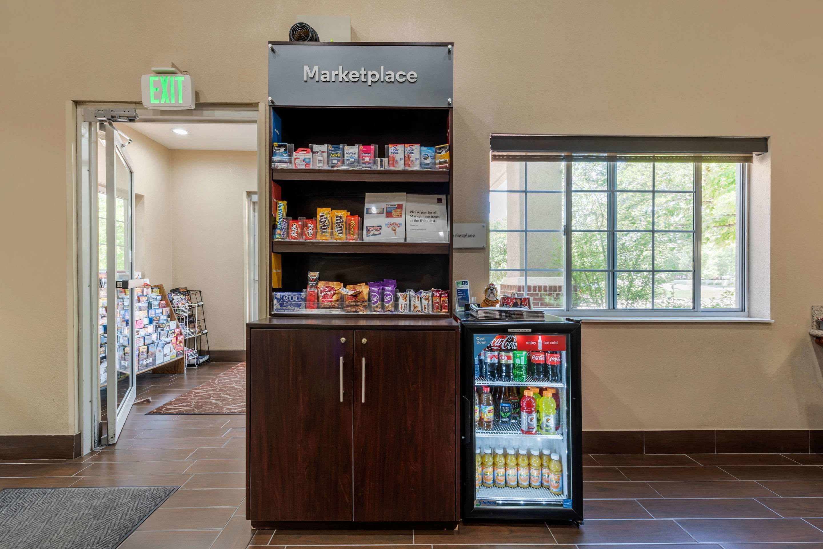 A marketplace with shelves stocked with snacks and a refrigerated display case with beverages.