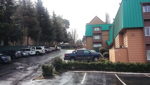 A parking lot with several cars and a building with a green roof. - Sutton Suites Hotel (SeaTac)