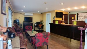 A hotel lobby with a reception desk, seating area with chairs, a television, and a vending machine. - Sutton Suites Hotel (SeaTac)