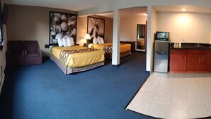 A hotel room with two beds, a sofa, a dining area, and a kitchen. - Sutton Suites Hotel (SeaTac)