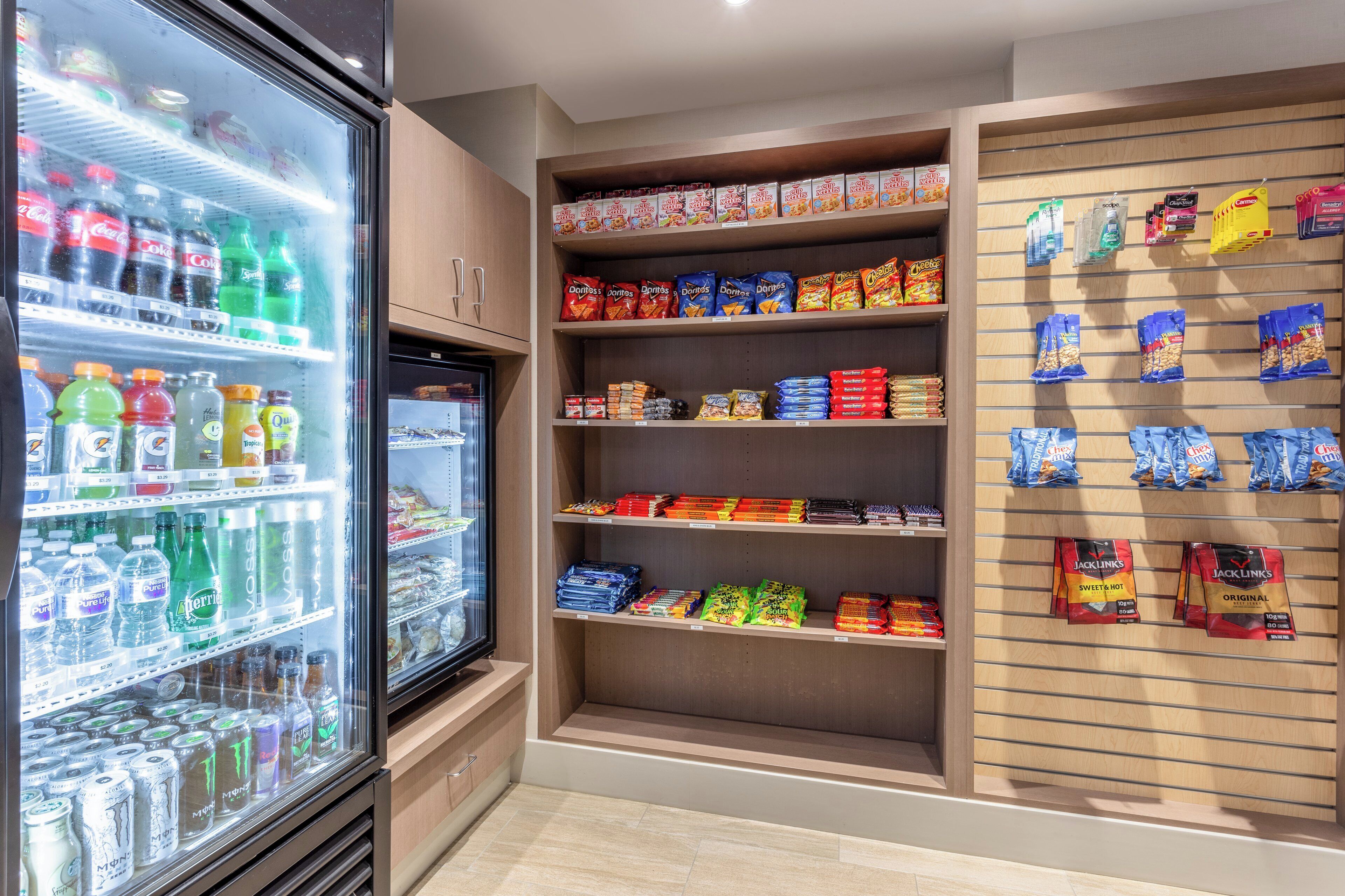 Un réfrigérateur à boissons rempli de diverses boissons et un espace dédié aux en-cas, avec des chips et d’autres produits à grignoter.