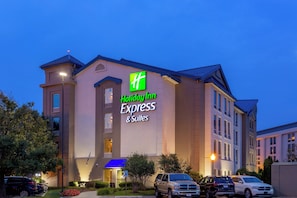 Ein Holiday Inn Express & Suites Hotel mit moderner Fassade, mehreren Parkplätzen und einem gut beleuchteten Eingang.