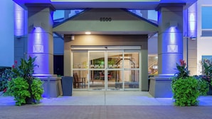 A hotel entrance with a glass door, a number 6500 sign above, and two signs indicating courtesy shuttle pick-up only. - Holiday Inn Express Hotel & Suites Chicago-Midway Airport by IHG (Chicago)