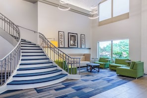 A modern interior with a staircase, green upholstered seating, and artwork on the walls. - Holiday Inn Express Hotel & Suites Chicago-Midway Airport by IHG (Chicago)
