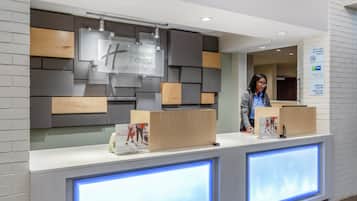 A hotel reception desk with a modern design, including a digital display and a sign indicating it is a non-smoking property.