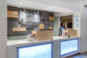 A hotel reception desk with a modern design, including a digital display and a sign indicating it is a non-smoking property. - Holiday Inn Express Hotel & Suites Chicago-Midway Airport by IHG (Chicago)