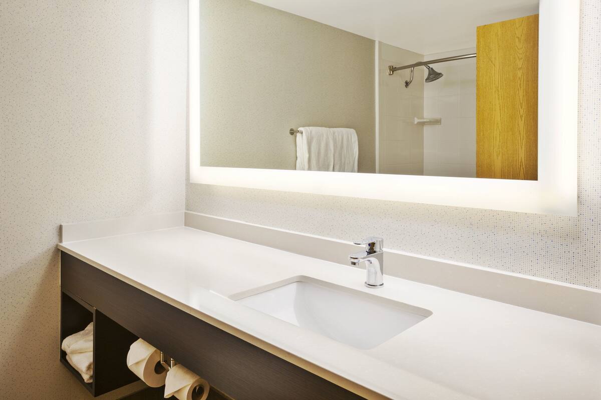 A bathroom with a white sink, a mirror, and a towel rack.