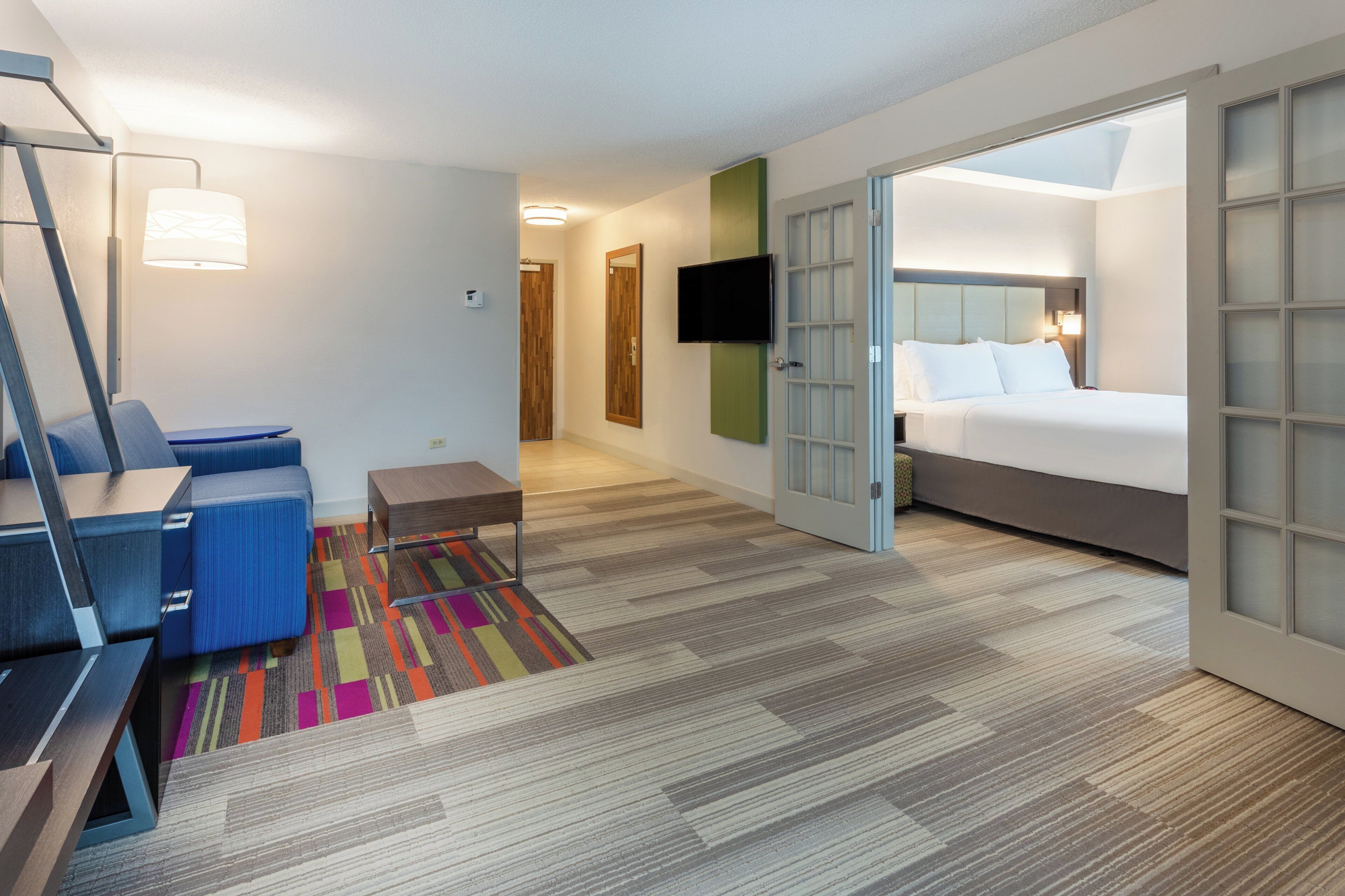 Una habitación de hotel con cama, escritorio, silla, televisor y baño.