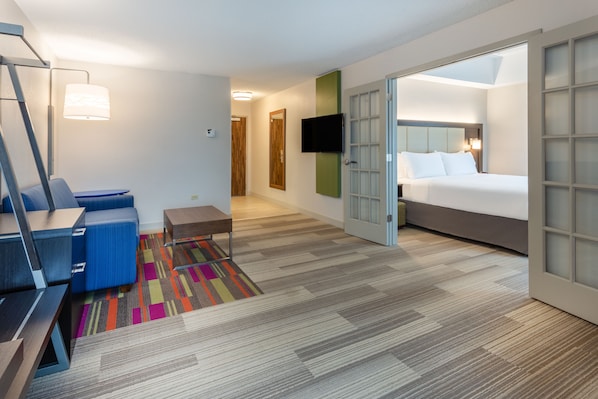 A hotel room with a bed, a desk, a chair, a TV, and a colorful rug. - Holiday Inn Express Hotel & Suites Chicago-Midway Airport by IHG (Chicago)