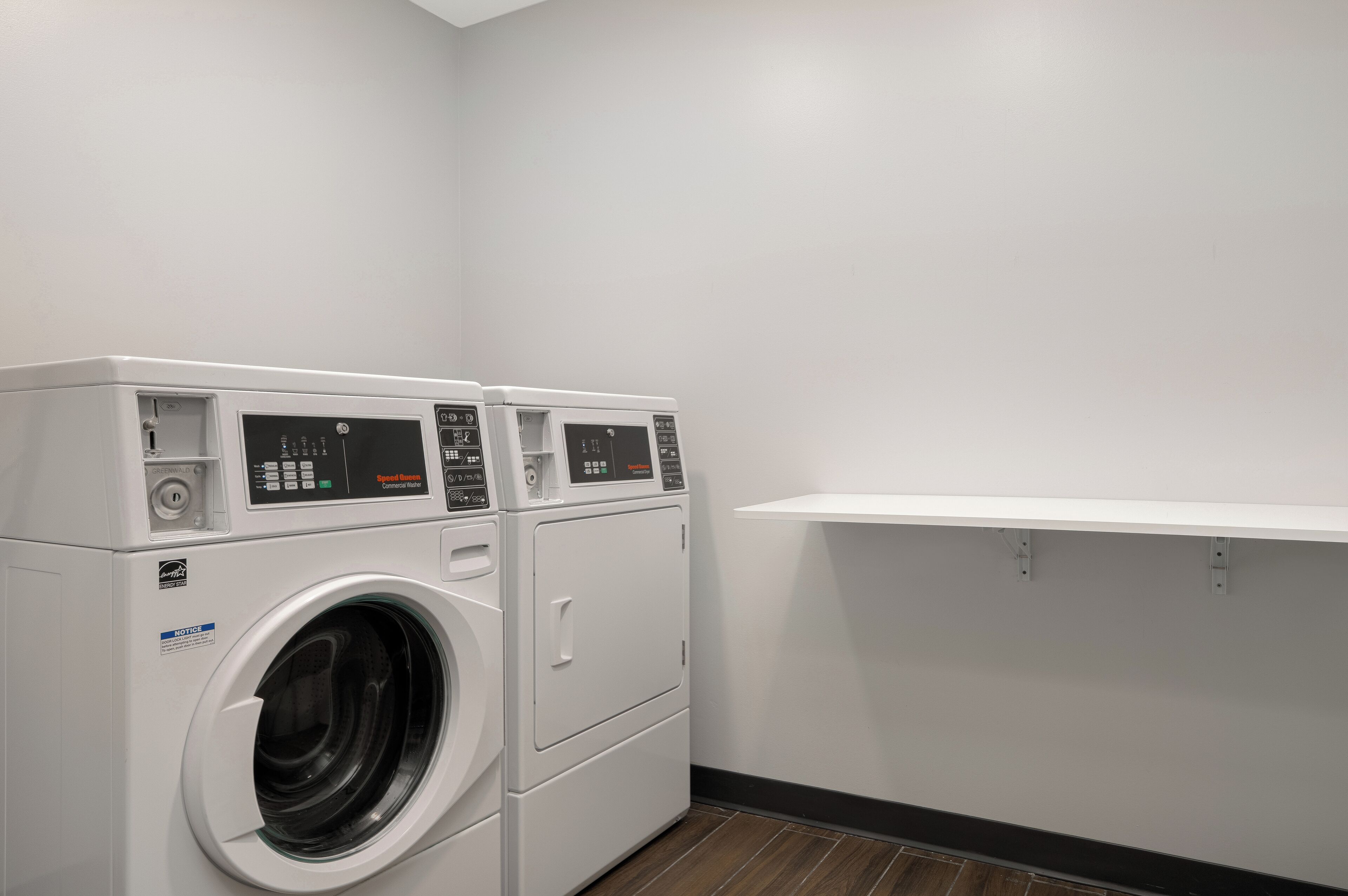 A laundry room with two stacked front-loading washing machines and a single dryer.