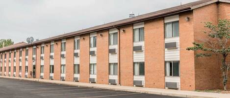 A long, single-story brick building with a row of windows and air conditioning units.