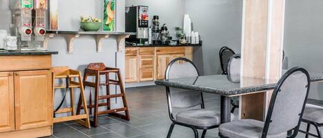 Una cocina moderna con armarios de madera, encimera de granito y comedor con mesa y sillas.