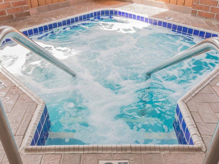A hot tub with a tiled border and metal steps.