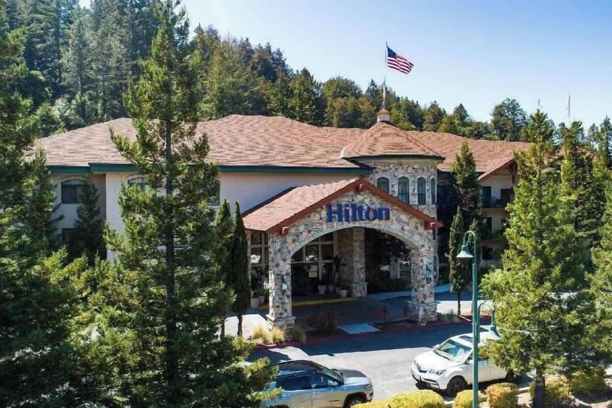 Ein Hotel mit steinbogigem Eingang, einer Flagge und von Bäumen umgeben.