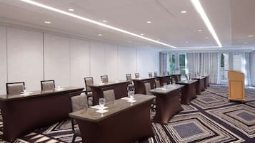 Un salón de conferencias con varias mesas, sillas y un atril.