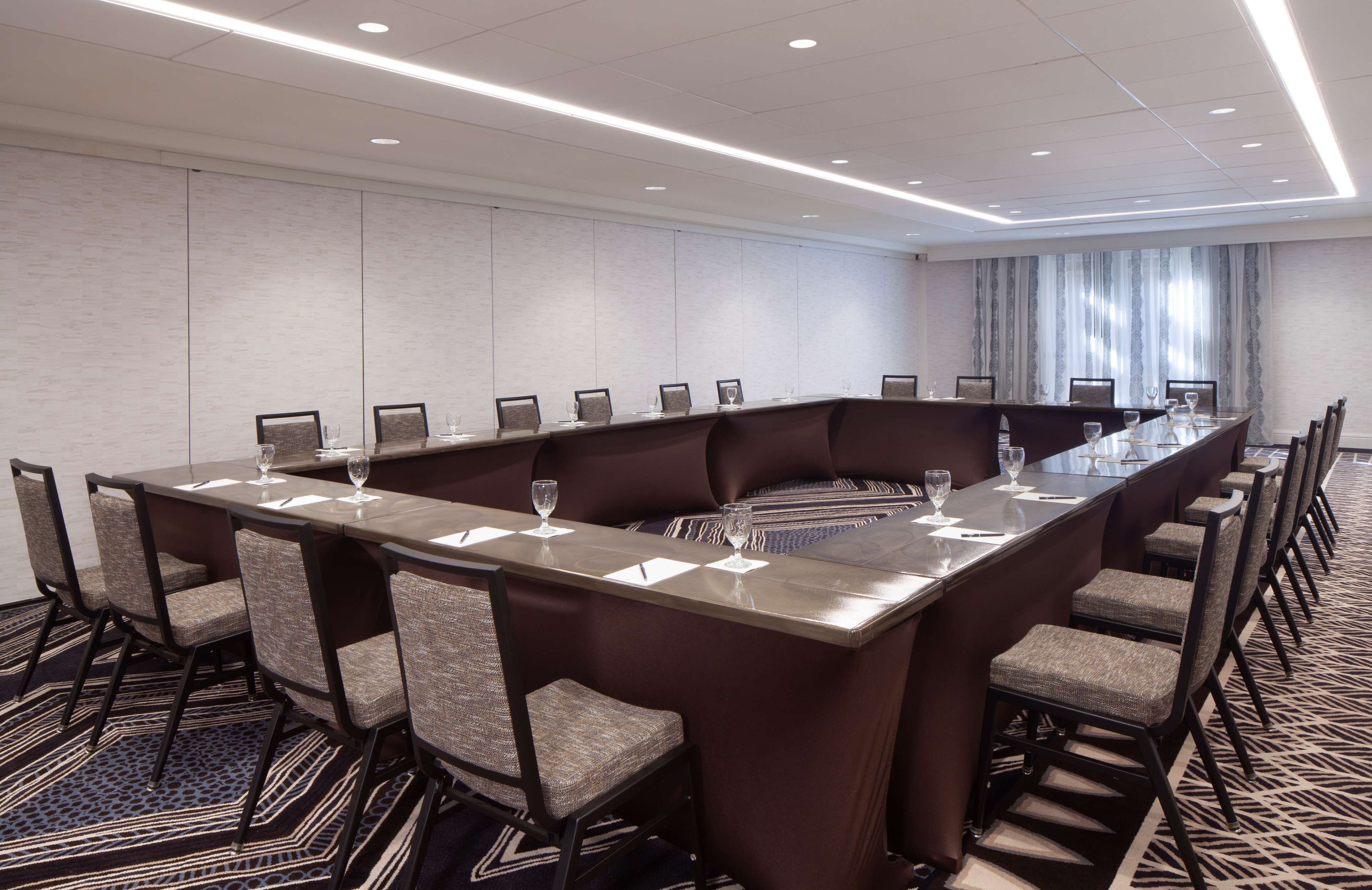 A conference room with a long table, chairs, and glassware.