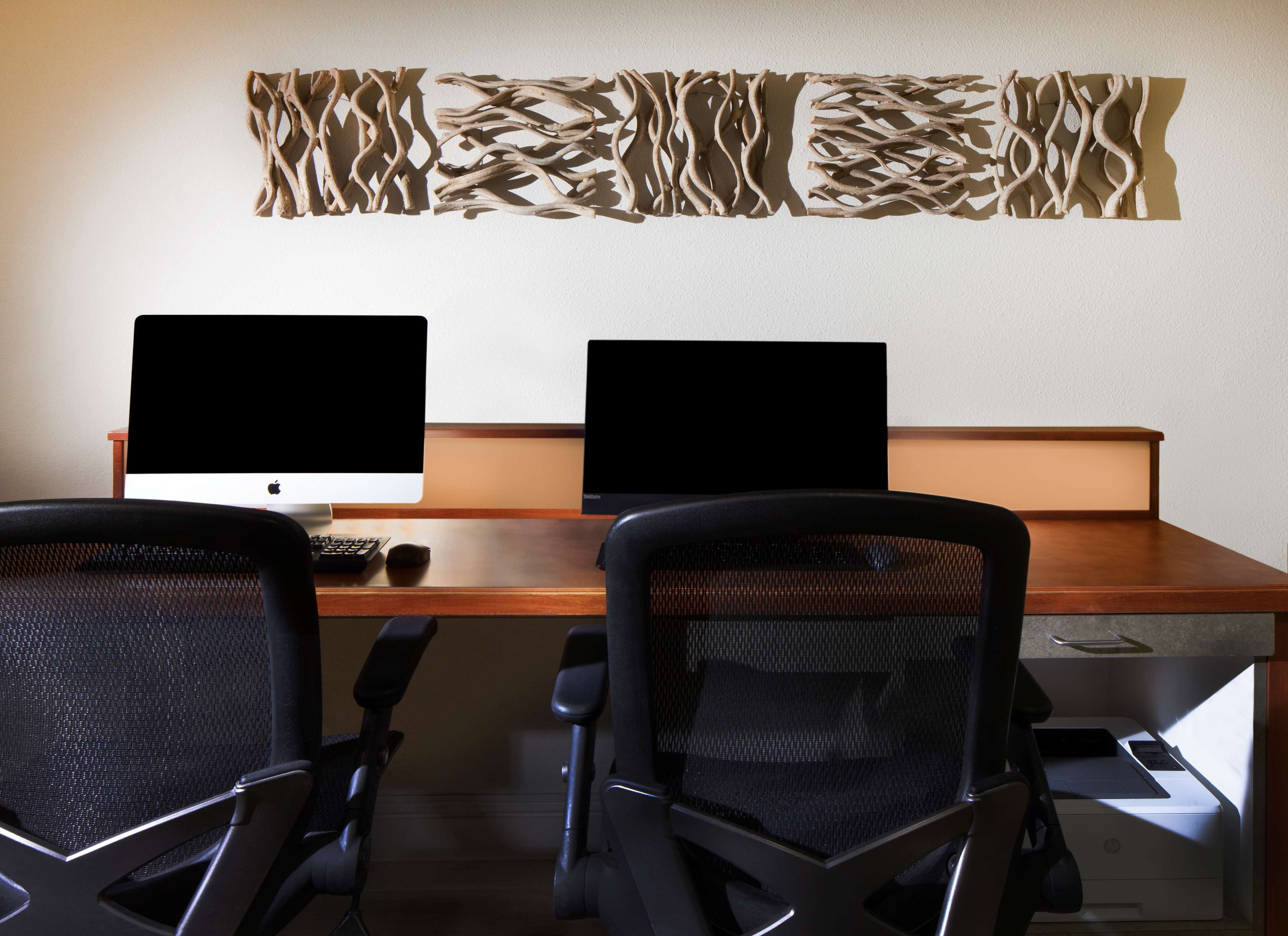 A workspace with two monitors, a keyboard, and two mesh office chairs.