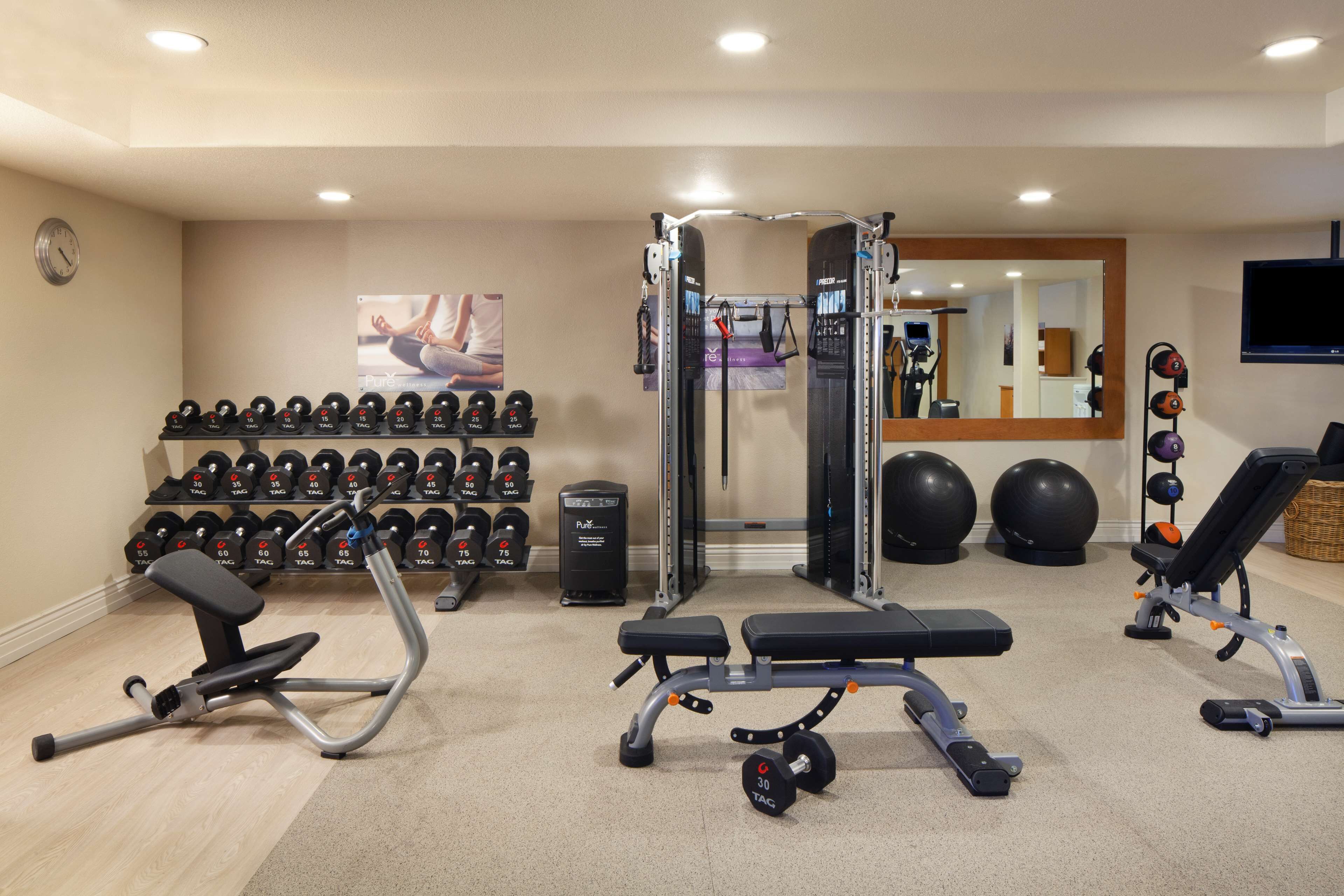 A gym with exercise equipment, dumbbells, and a mirror.