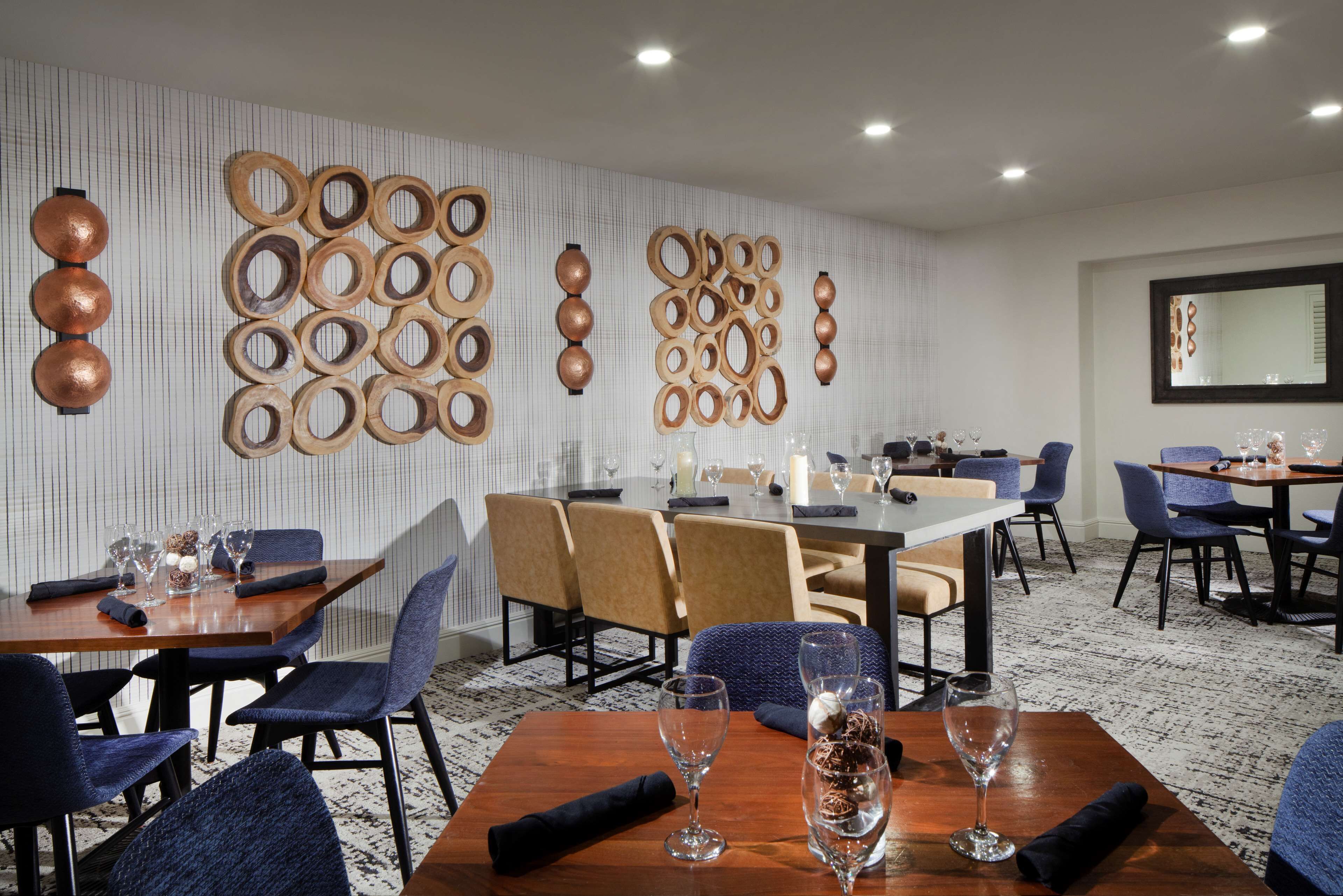 Un espace repas agrémenté de décorations murales en bois, de tables accompagnées de chaises et de verres à vin.