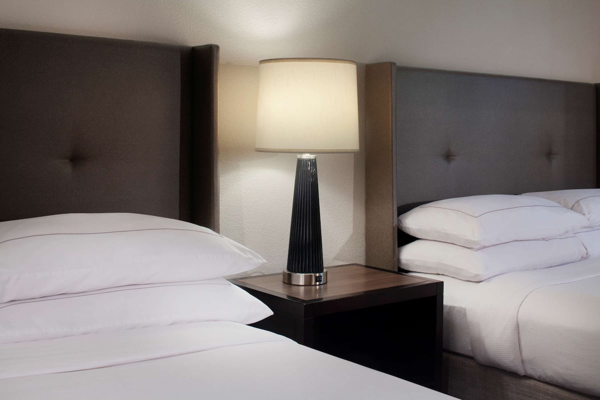Ein Hotelzimmer mit Bett, Nachttisch und Lampe sowie einer Kopfteil.