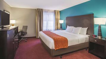 Une chambre d’hôtel avec un grand lit, un bureau équipé d’un ordinateur, une télévision et une chaise.