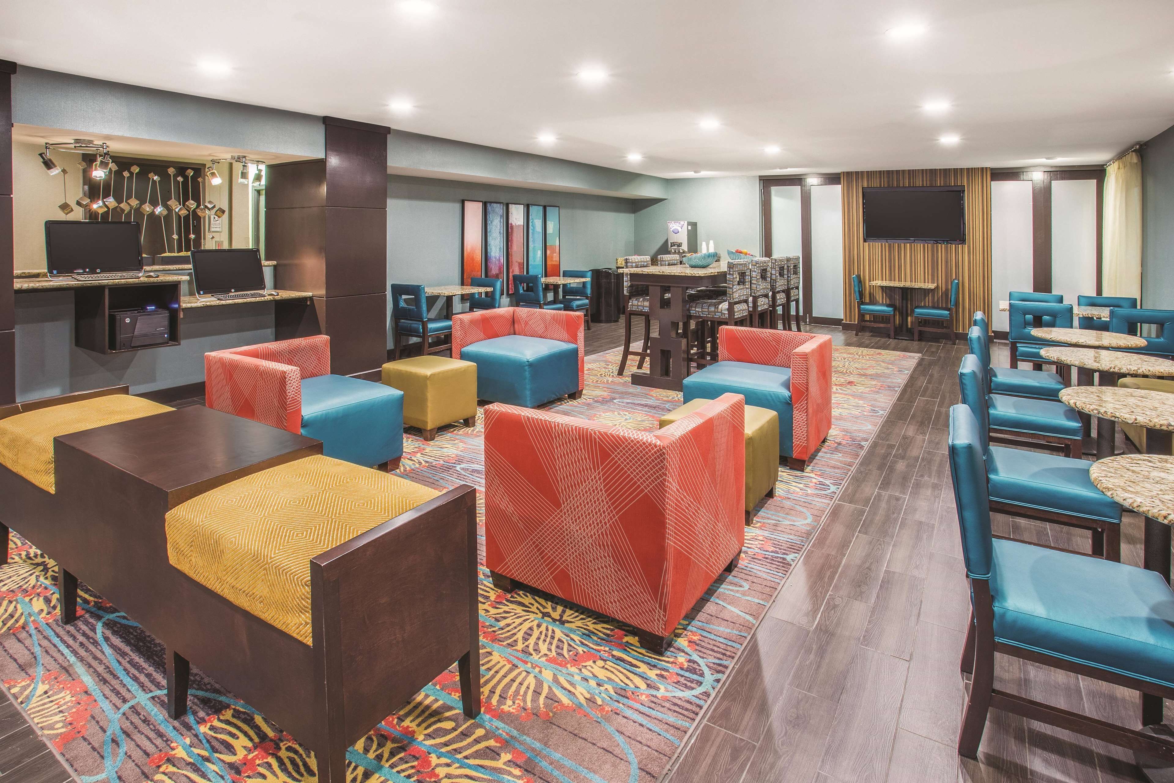 A hotel lobby with multiple seating areas, a bar, and a television screen.