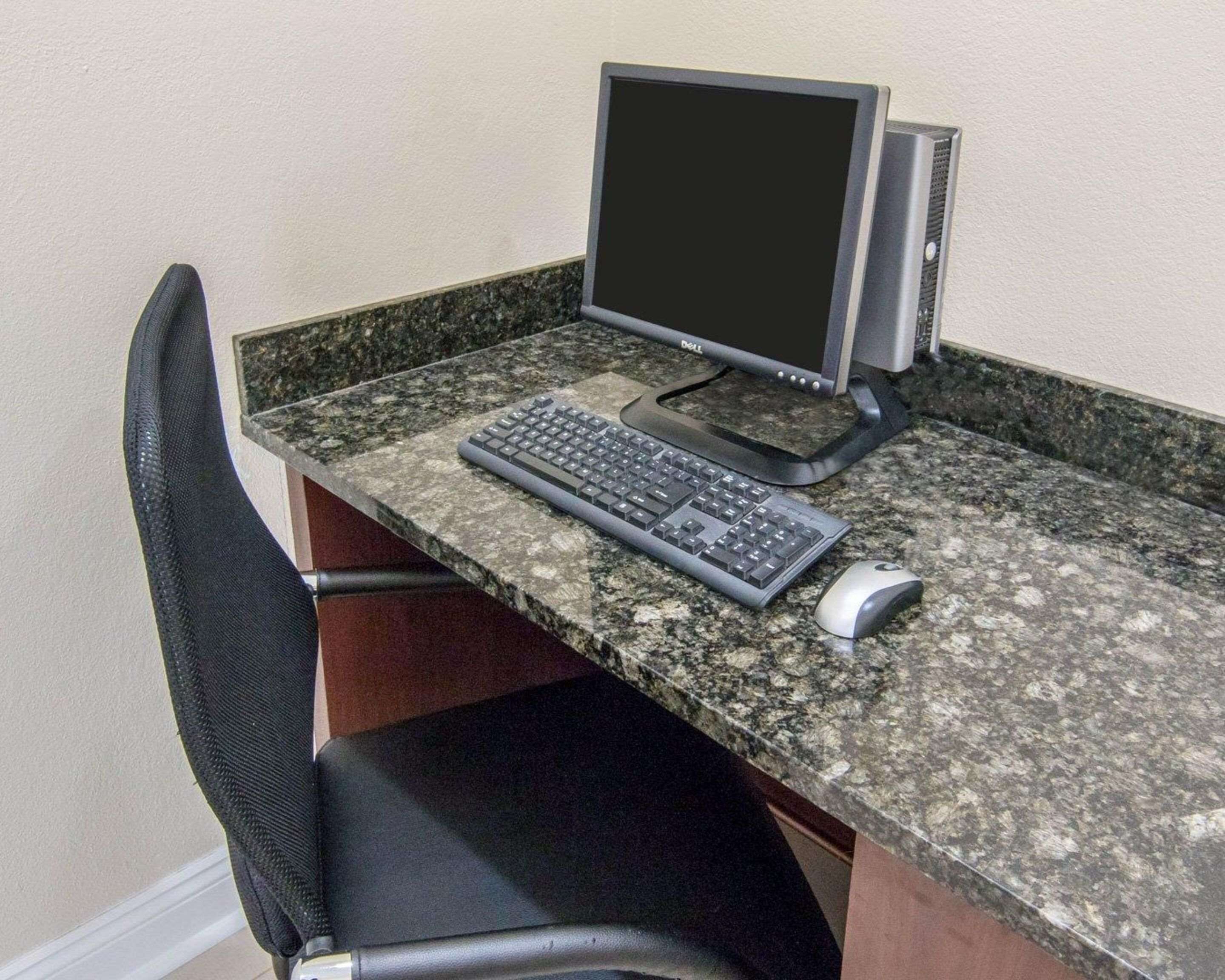 Uma mesa de escritório com um computador, teclado e rato.