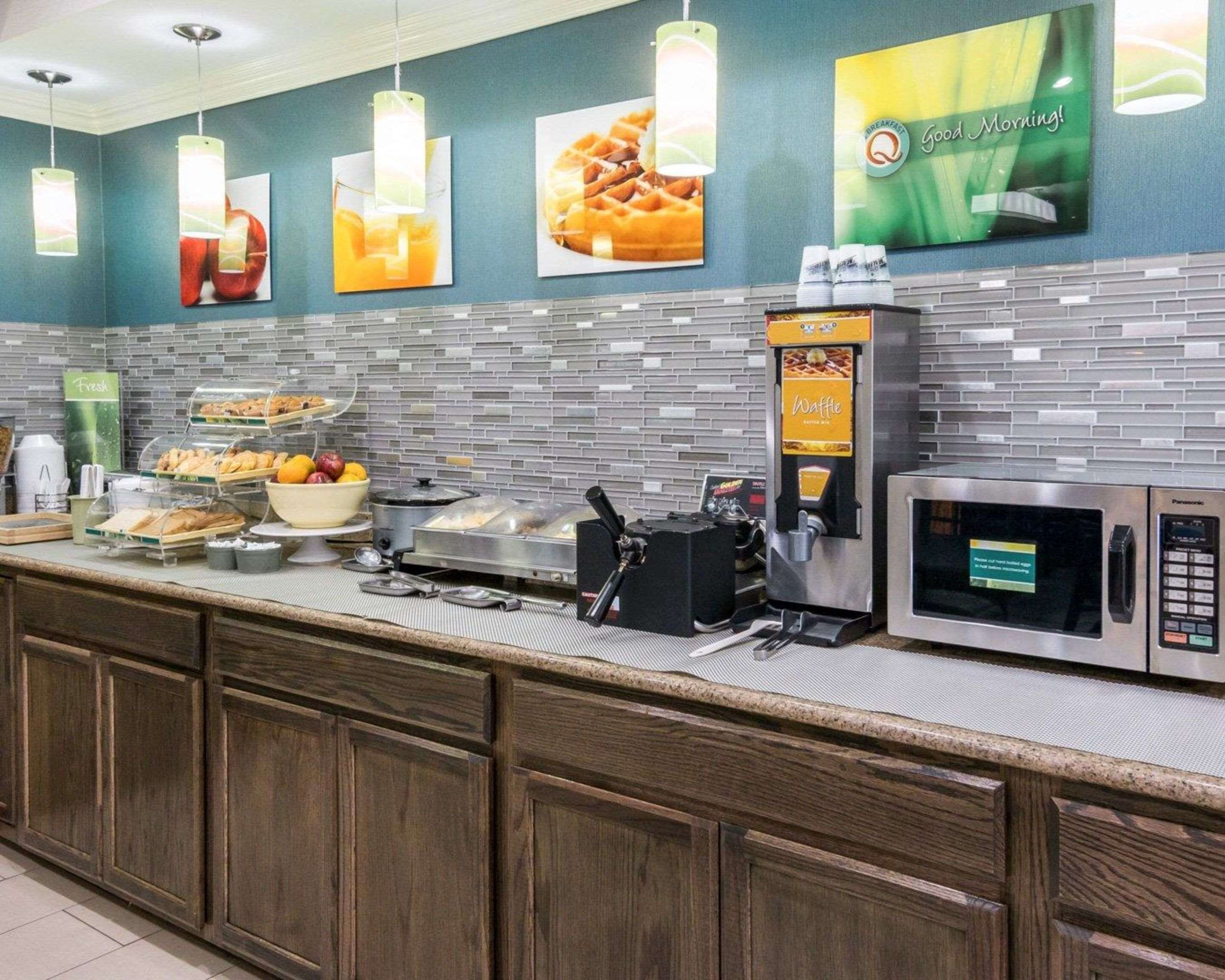 A breakfast bar with a waffle maker, coffee machine, and microwave.