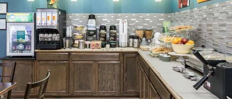 A breakfast bar with a vending machine, coffee makers, and a variety of breakfast items.