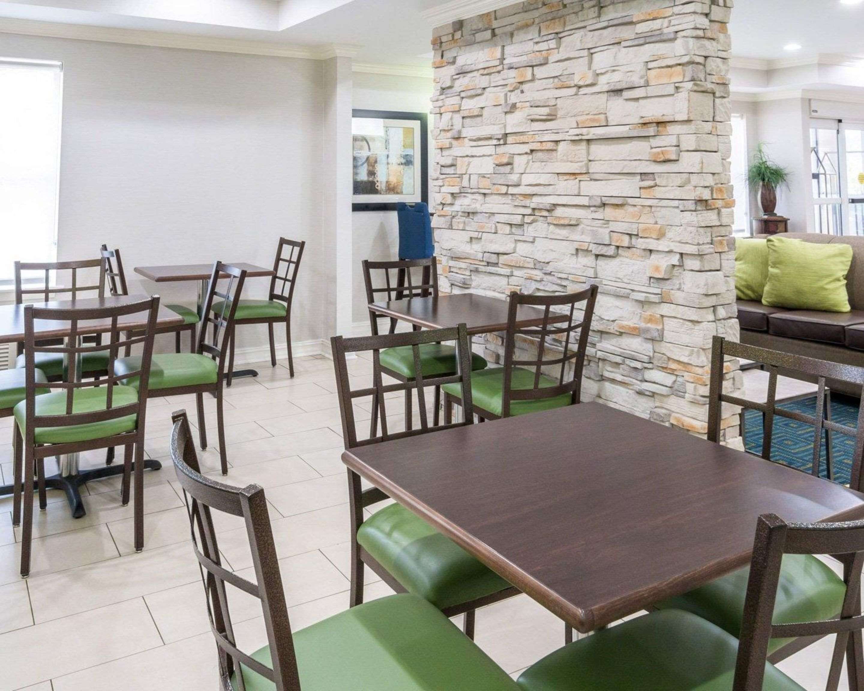 A dining area with tables and chairs, a stone wall, and a sofa with cushions.